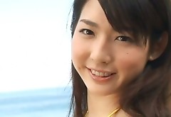 Radiating Japanese beauty Nanako Sawa poses on a beach wearing sexy yellow swimsuit