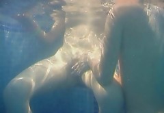 Seductive brunette lesbians tickle their snatches under water in pool