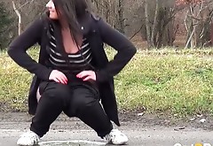 Lewd brunette chick pisses outdoors right on the parking lot outdoors