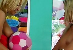 Two blonde teenage girls are on a bed playing a ball game. They lower their shirts, showing their pert tits. Then they take each others shirts off so 